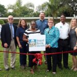 Broward Housing Solutions employees posing behind red ribbon