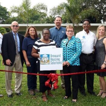 Broward Housing Solutions employees posing behind red ribbon