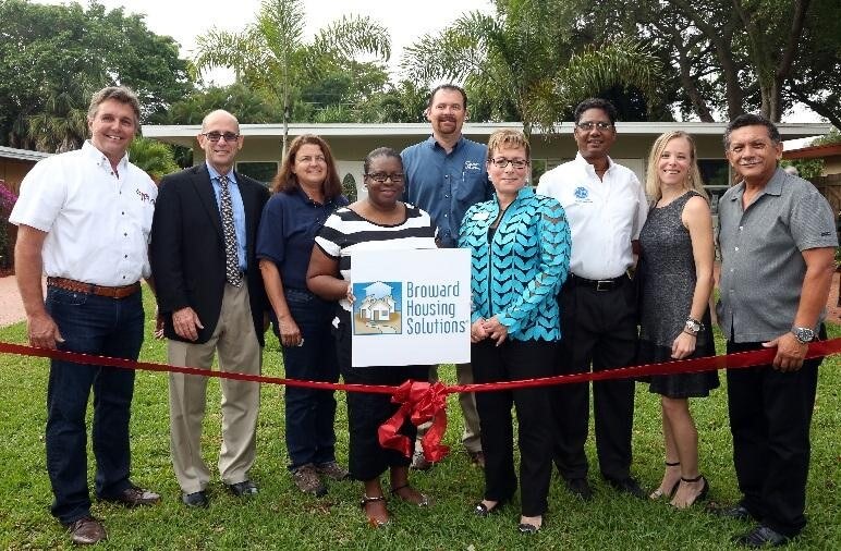 Broward Housing Solutions employees posing behind red ribbon