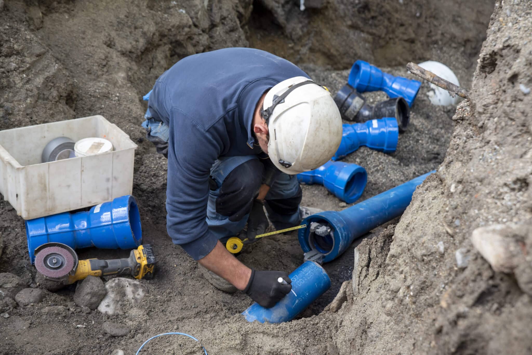 worker installing underground pipes for sewer