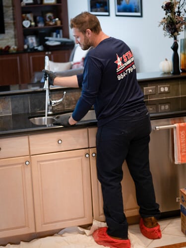 Plumber clearing a clogged kitchen drain 